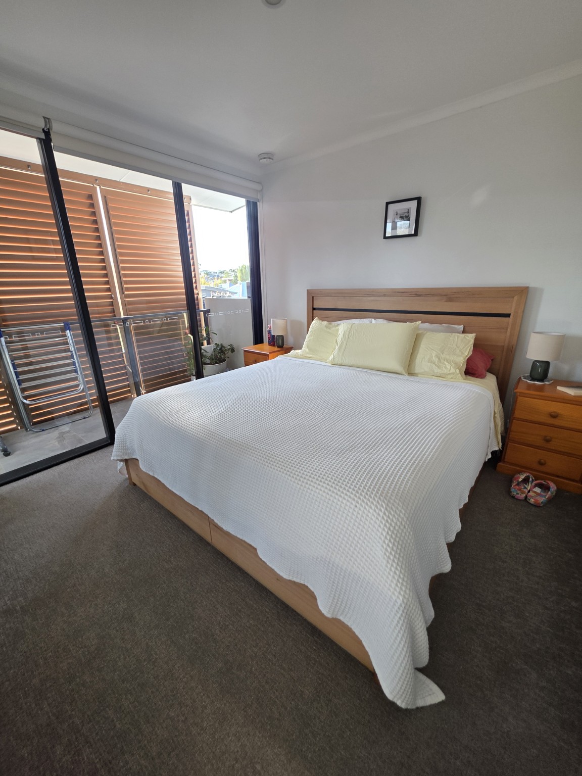 Tidy bedroom with a white bedspread and timber bed frame