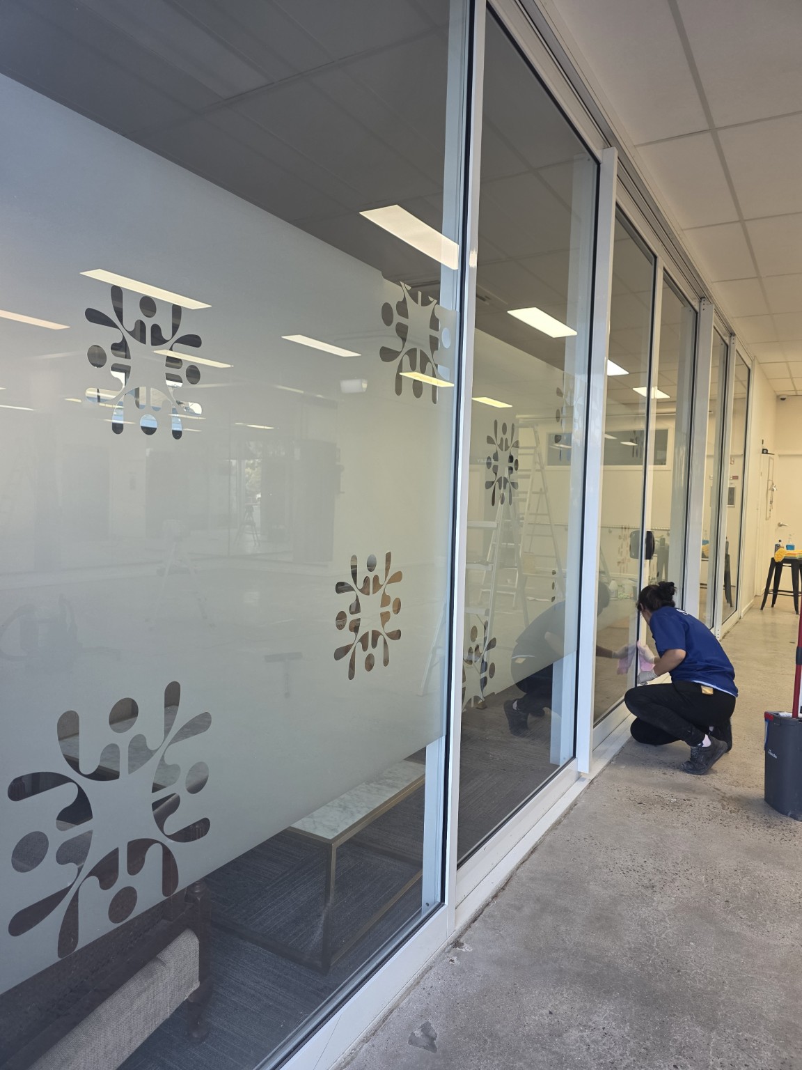 Team member cleaning the lower glass and frames of commercial partitions
