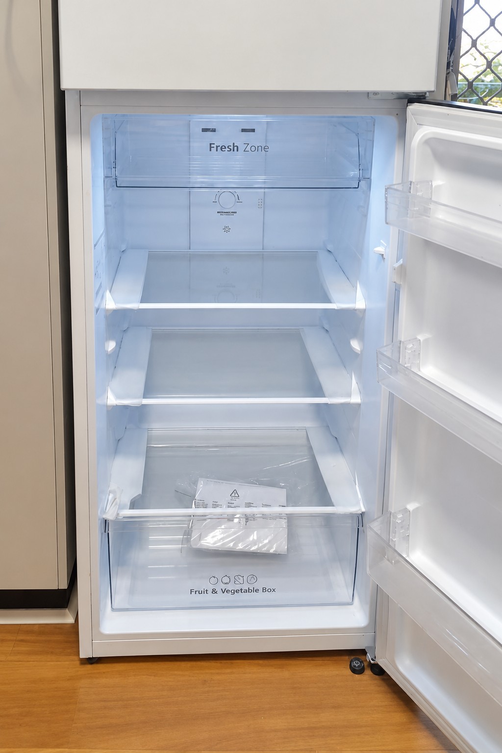 Open refrigerator showing the glass shelves, vegetable drawer and door compartments