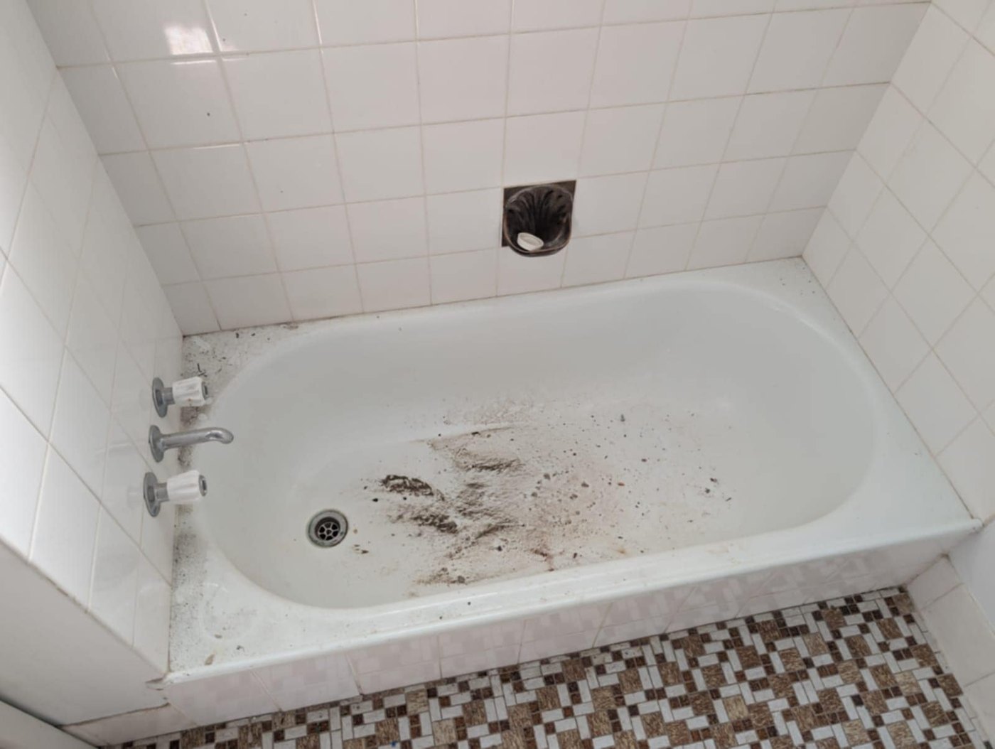 Bathtub before cleaning, with visible dirt and debris in the basin