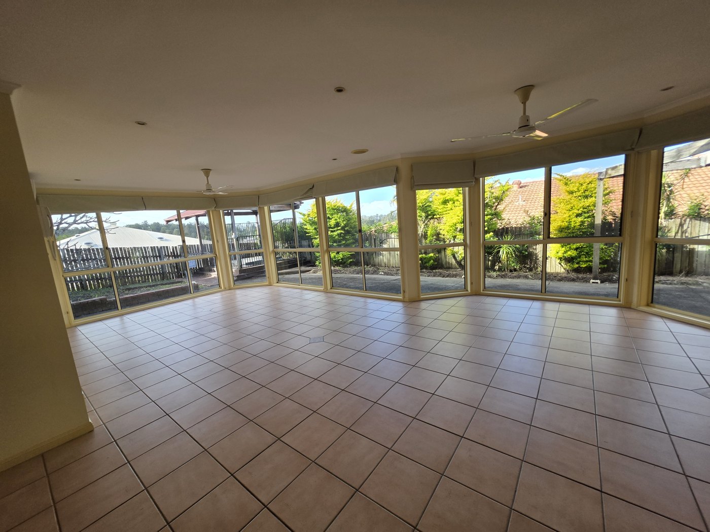Clean empty tiled living room with large windows opening onto a garden
